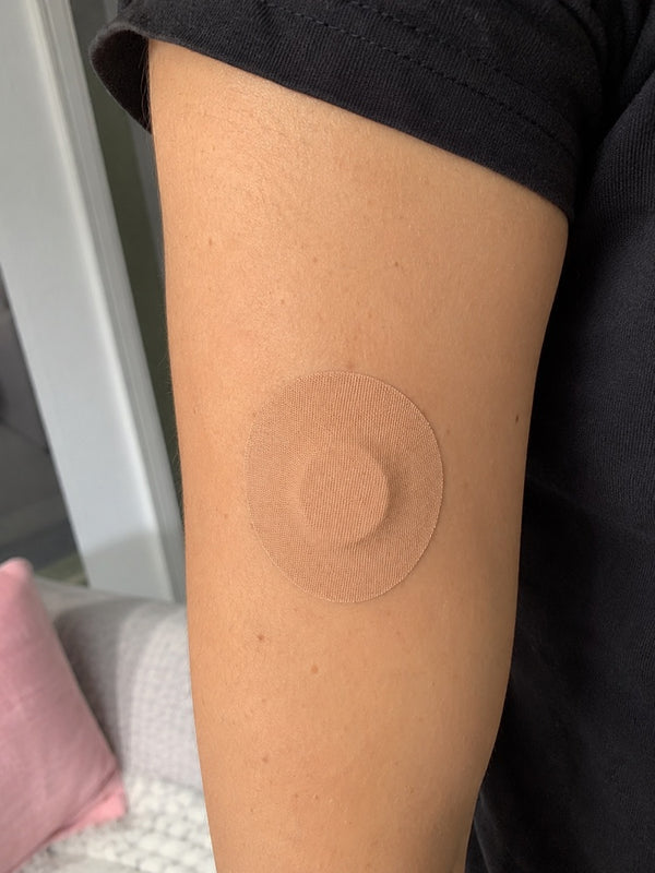Parche Patch Me Up beige puesto sobre el sensor en el brazo, primer plano